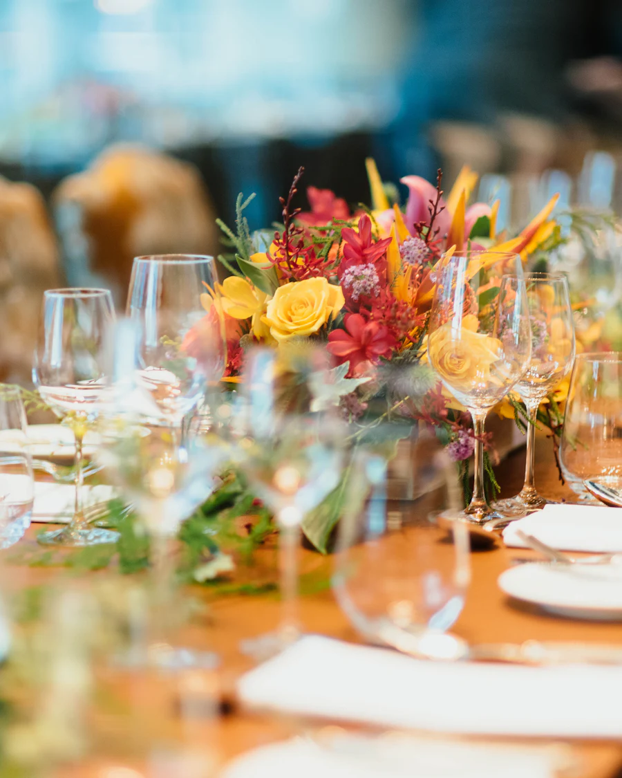 A long celebration table set with glassware, plates, and a floral centerpiece